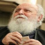 جناب هوشنگ ابتهاج با لباس های مشکی و ریش و موی سفید که دارن به دور دست نگاه میکنن