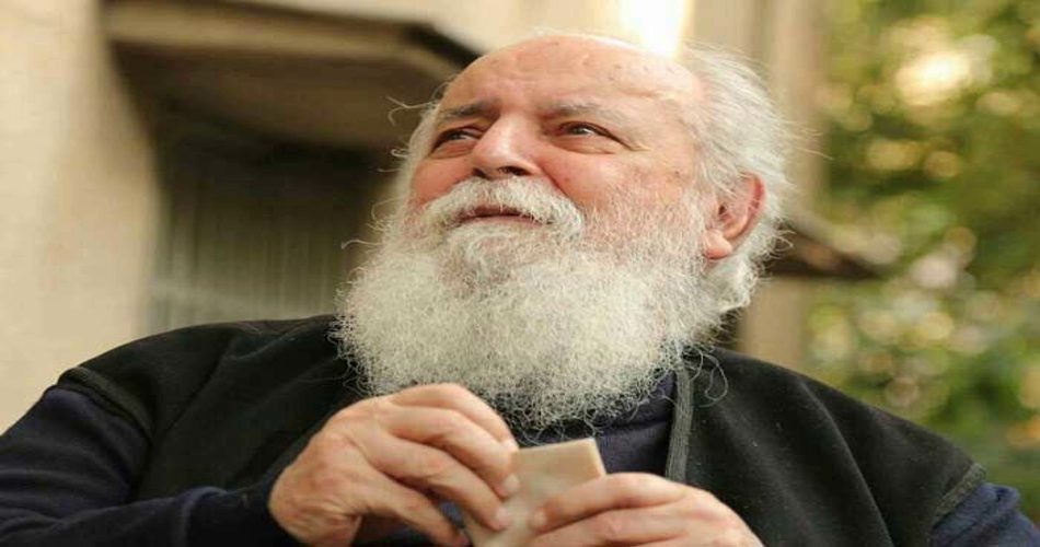 جناب هوشنگ ابتهاج با لباس های مشکی و ریش و موی سفید که دارن به دور دست نگاه میکنن