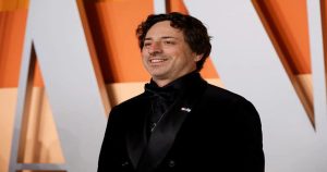 مردیبا ست رسمی کت شلوار مشکی لبخندی بر صورت دارد و در یک مصاحبه حاضر شده است