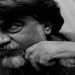 تصویری از قیصر امین پور{تصویری از مردی با ریش سفید و موهای جوگندمی تصویری سیاه و سفید که دارد به سمت چپ نگاه میکند}