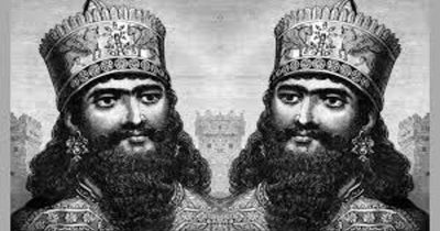 کمبوجیه دومه؛ یک پادشاه هخامنشی با تاج سلطنتی و ریش بلند، در سبک نقاشی تاریخی ایرانی، با لباس مزین و پس‌زمینه‌ی معماری باستانی شبیه تخت‌جمشید، حالت باشکوه و سلطنتی.